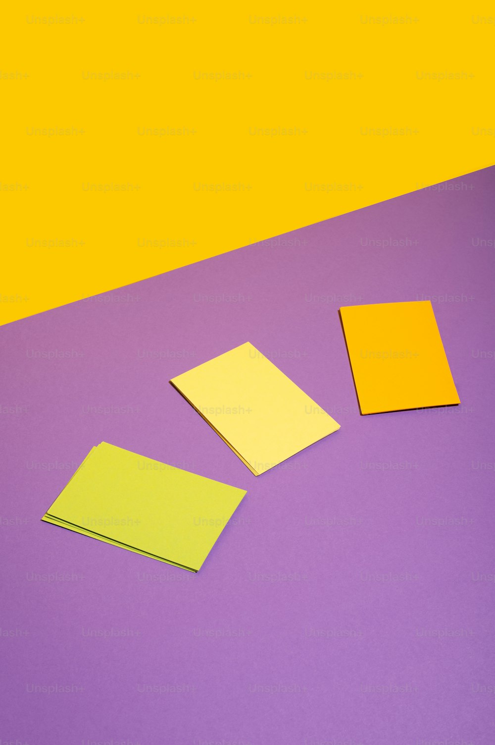 três pedaços de papel amarelo e roxo em um fundo roxo e amarelo