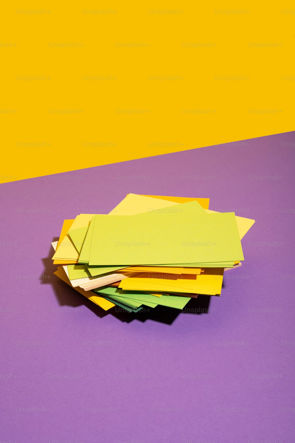 紫と黄色の背景に黄色と緑の紙の山