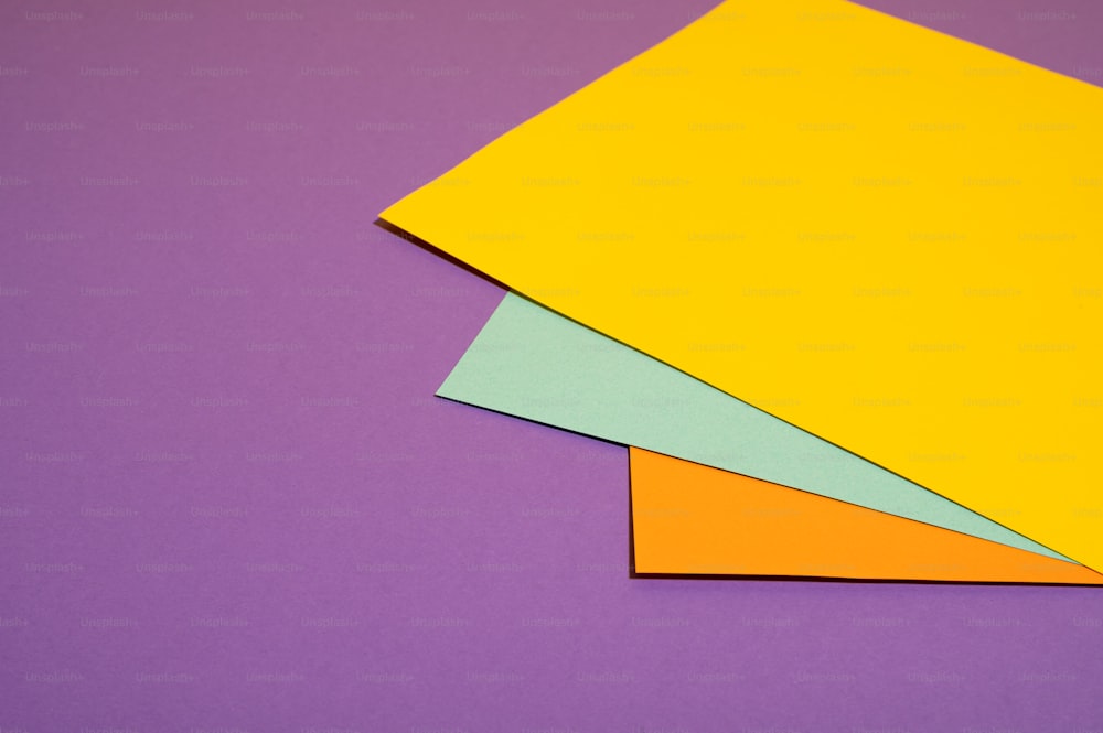 Tres hojas de papel de diferentes colores sobre un fondo púrpura