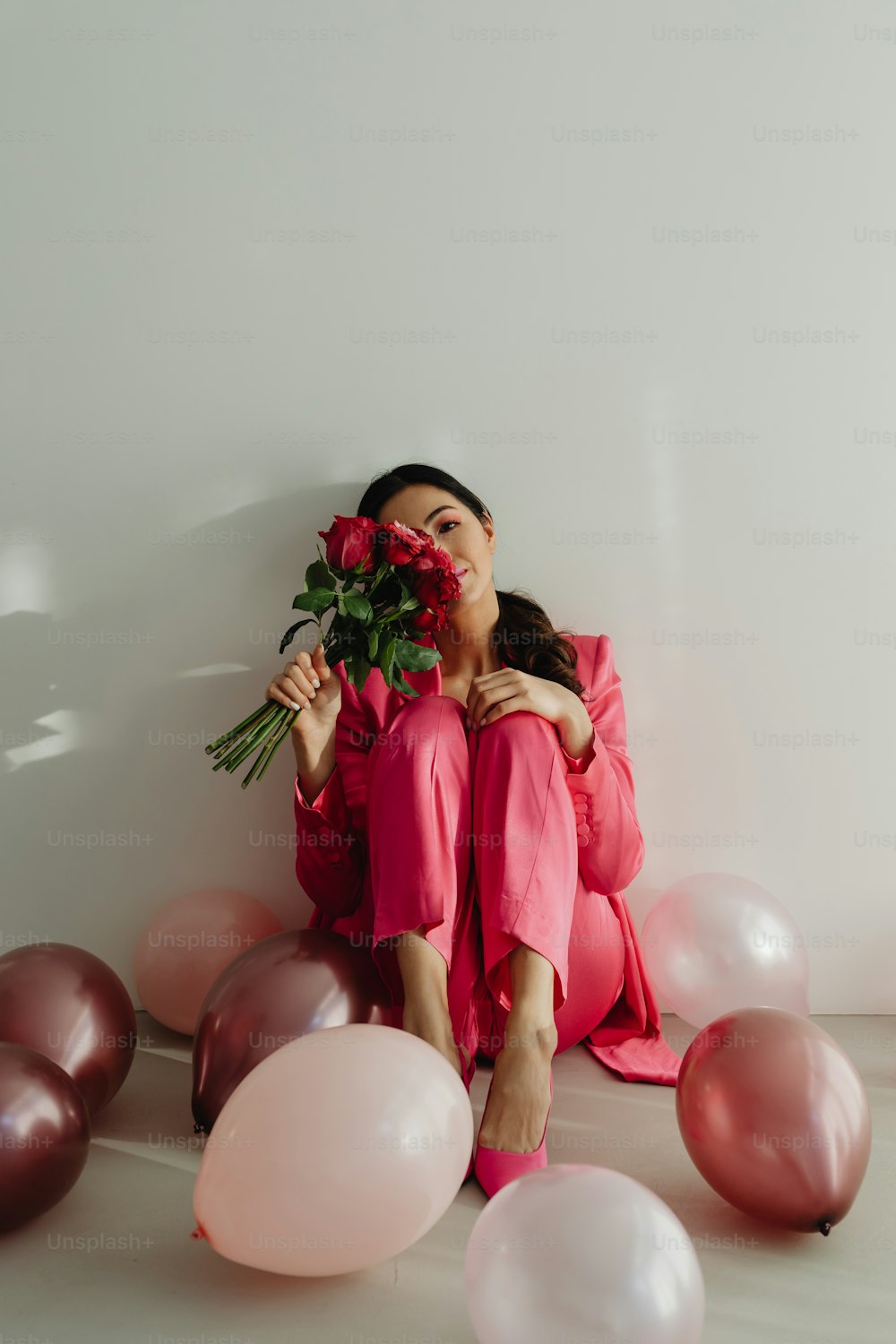 a woman sitting on the floor with balloons and flowers