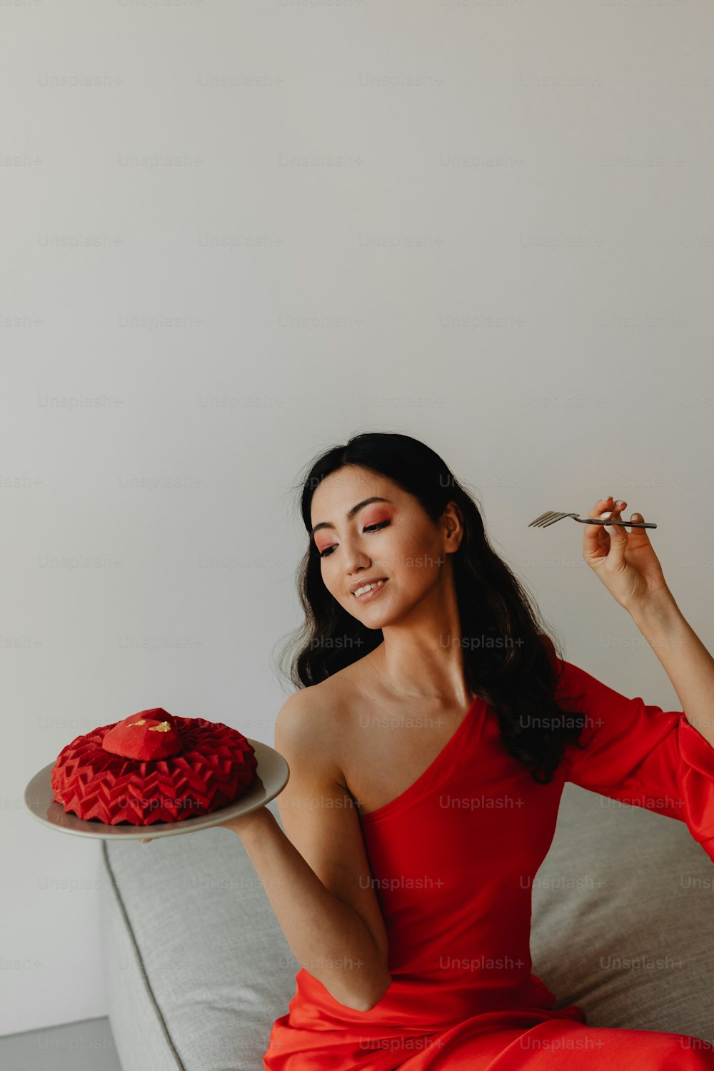 Una mujer con un vestido rojo sosteniendo un plato con un pastel