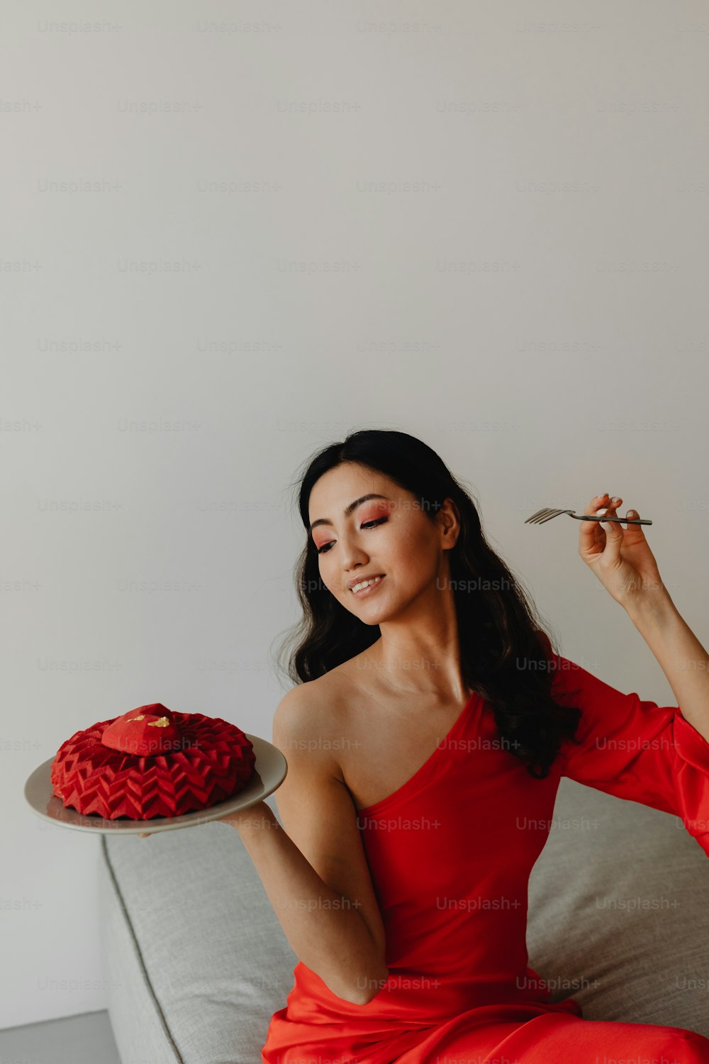 a woman in a red dress holding a plate with a cake on it