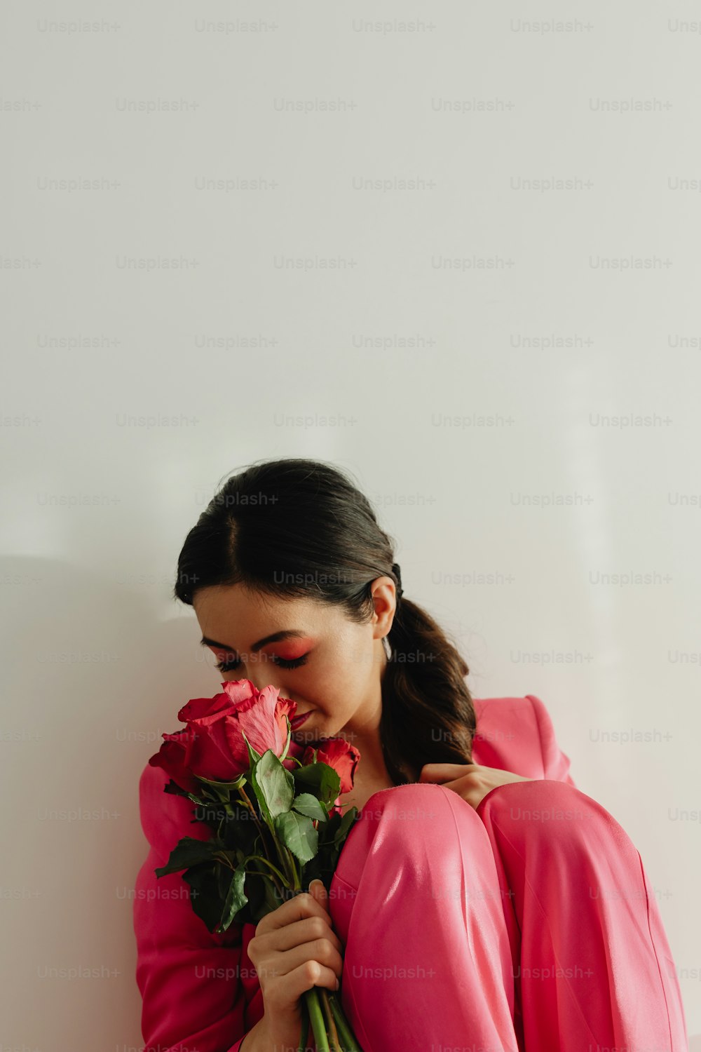 a woman in a pink dress holding a bouquet of roses