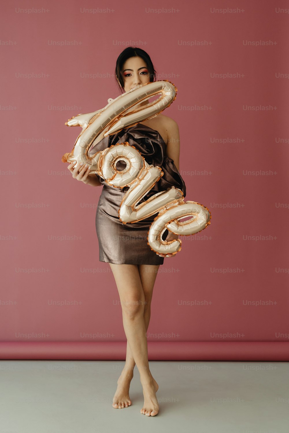 Eine Frau in einem kurzen Kleid, die einen großen Zahlenballon hält