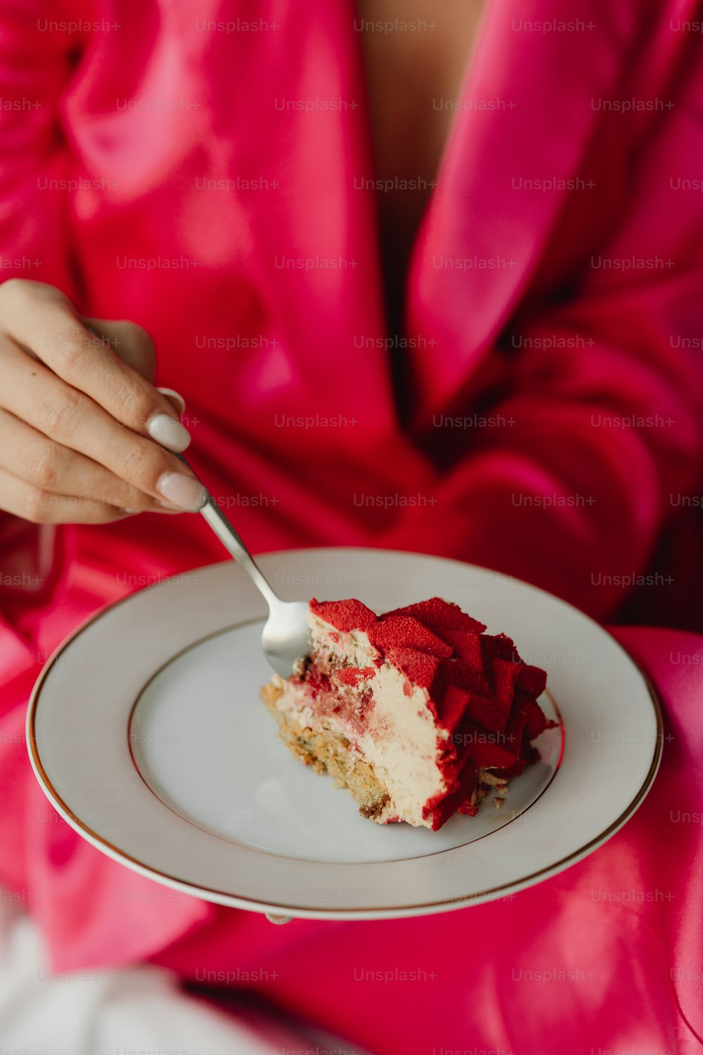 a woman in a pink dress eating a piece of cake