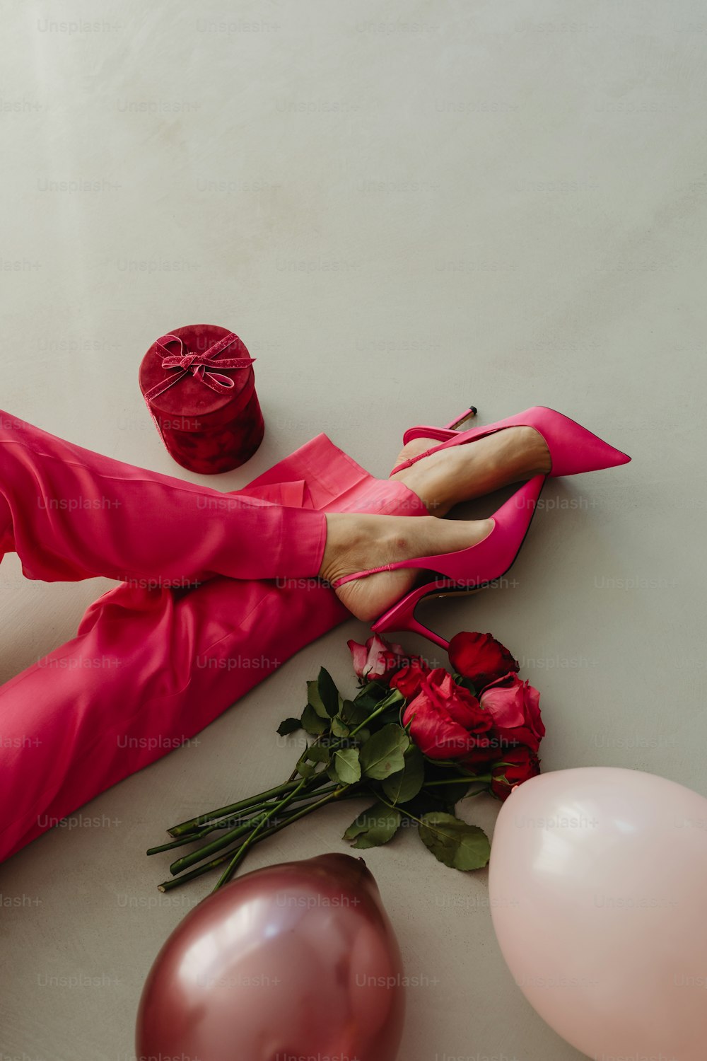 pés de uma mulher em sapatos cor-de-rosa ao lado de balões e balões