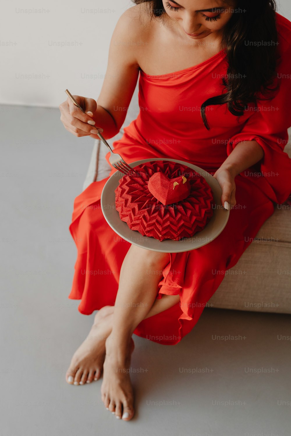 Eine Frau in einem roten Kleid hält einen herzförmigen Kuchen