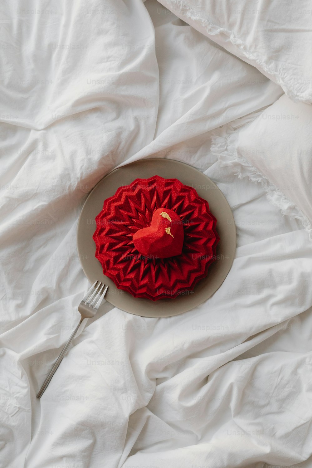 Ein roter Kuchen sitzt auf einem weißen Teller