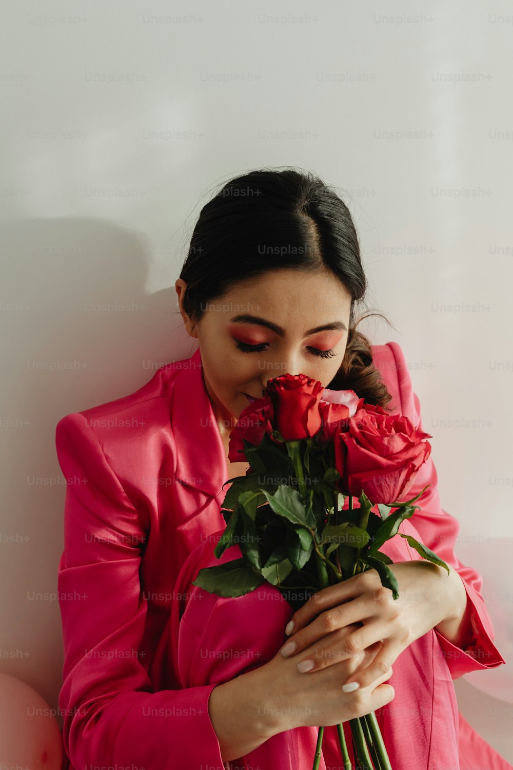 a woman in a pink suit holding a red rose
