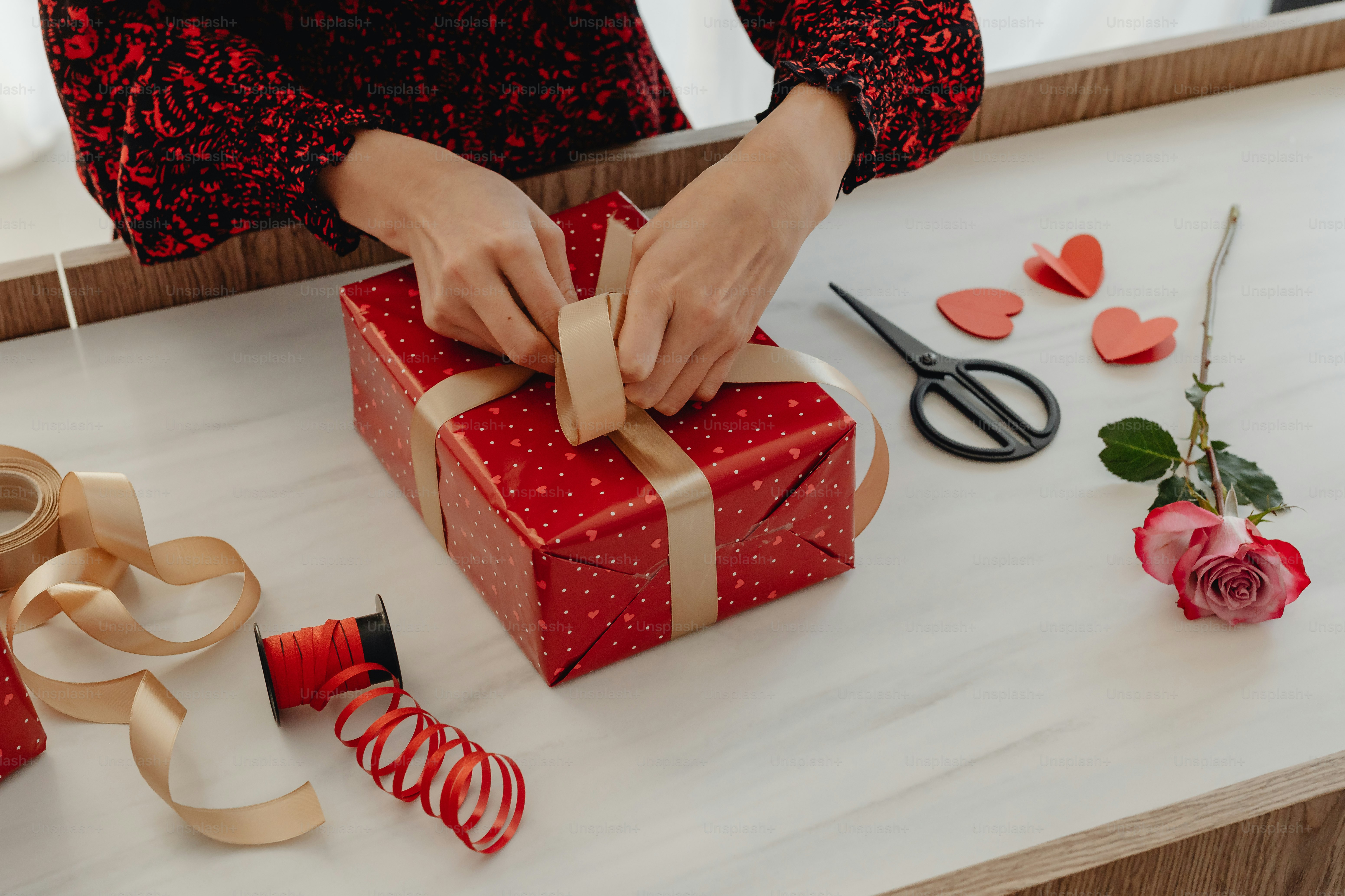 A woman is wrapping a gift on a table photo February 14th Image on