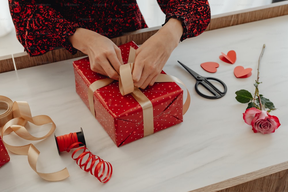a woman is wrapping a gift on a table