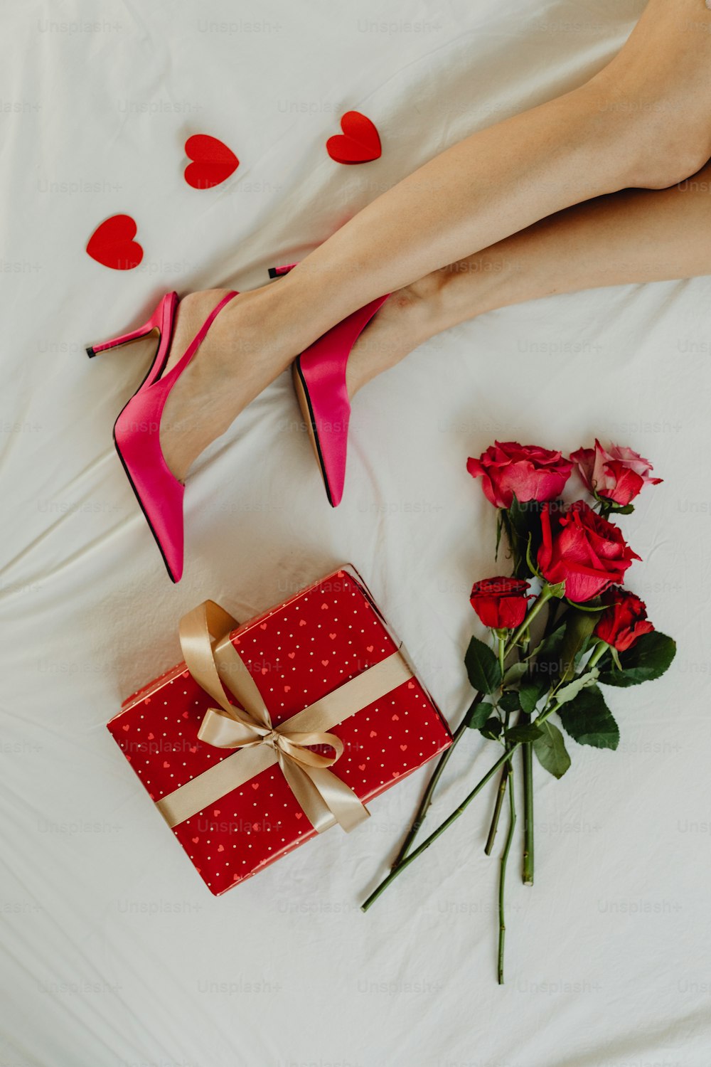 a woman laying in bed with a gift and roses