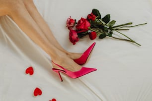 a woman's legs and heels on a bed with roses