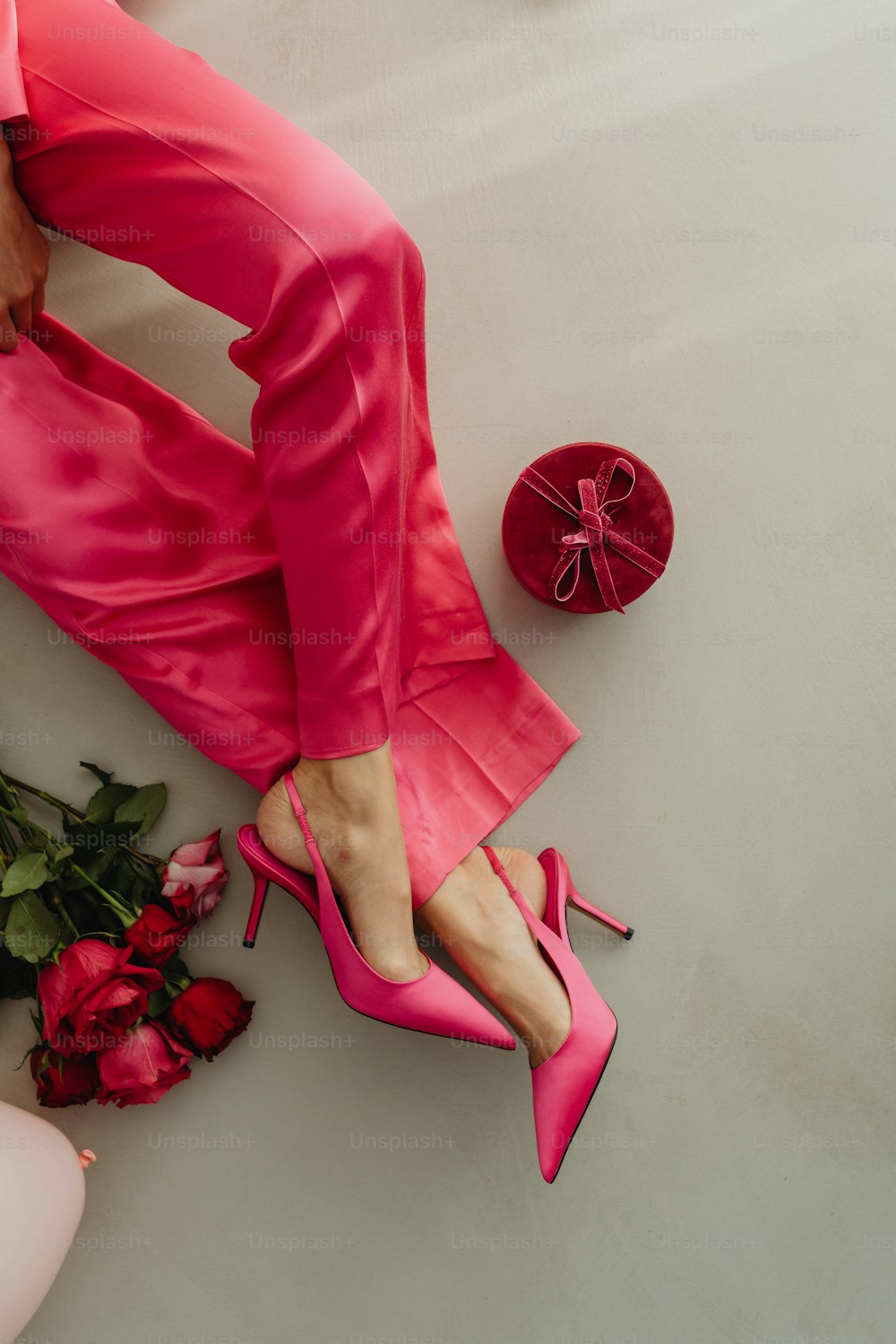 a woman's feet in pink shoes next to a bouquet of roses