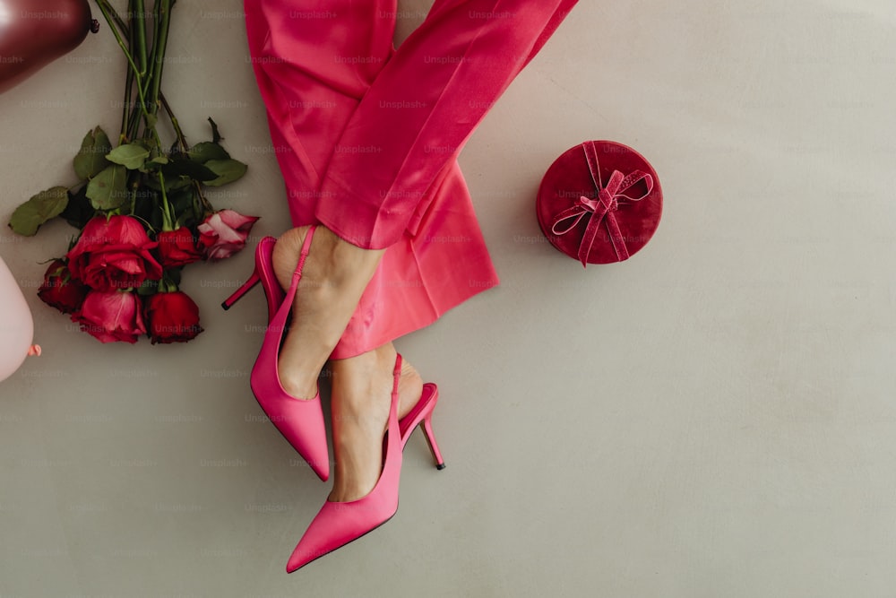 pés de uma mulher em sapatos cor-de-rosa ao lado de um buquê de rosas