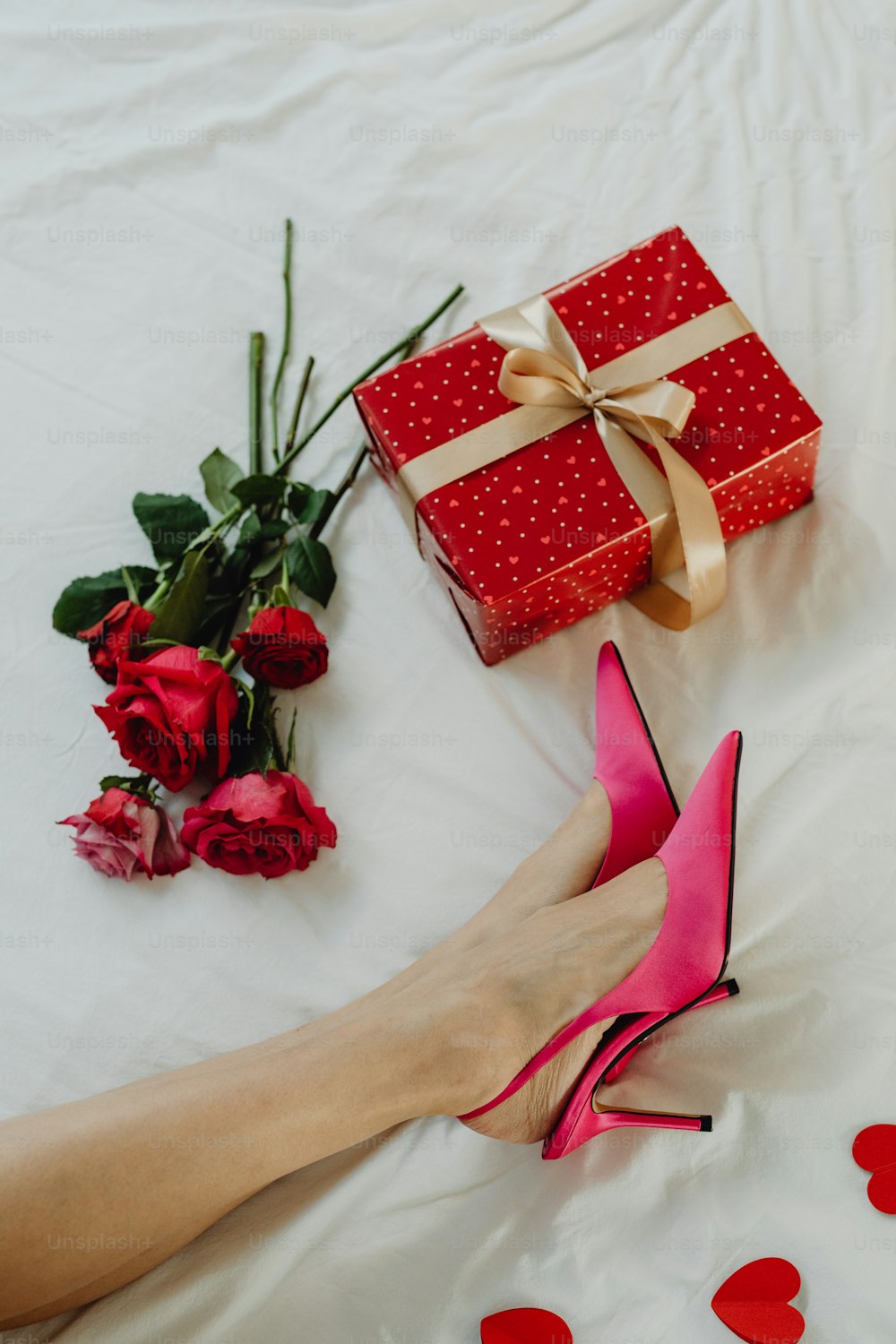 a woman's hand holding a pink high heel shoe next to a gift box