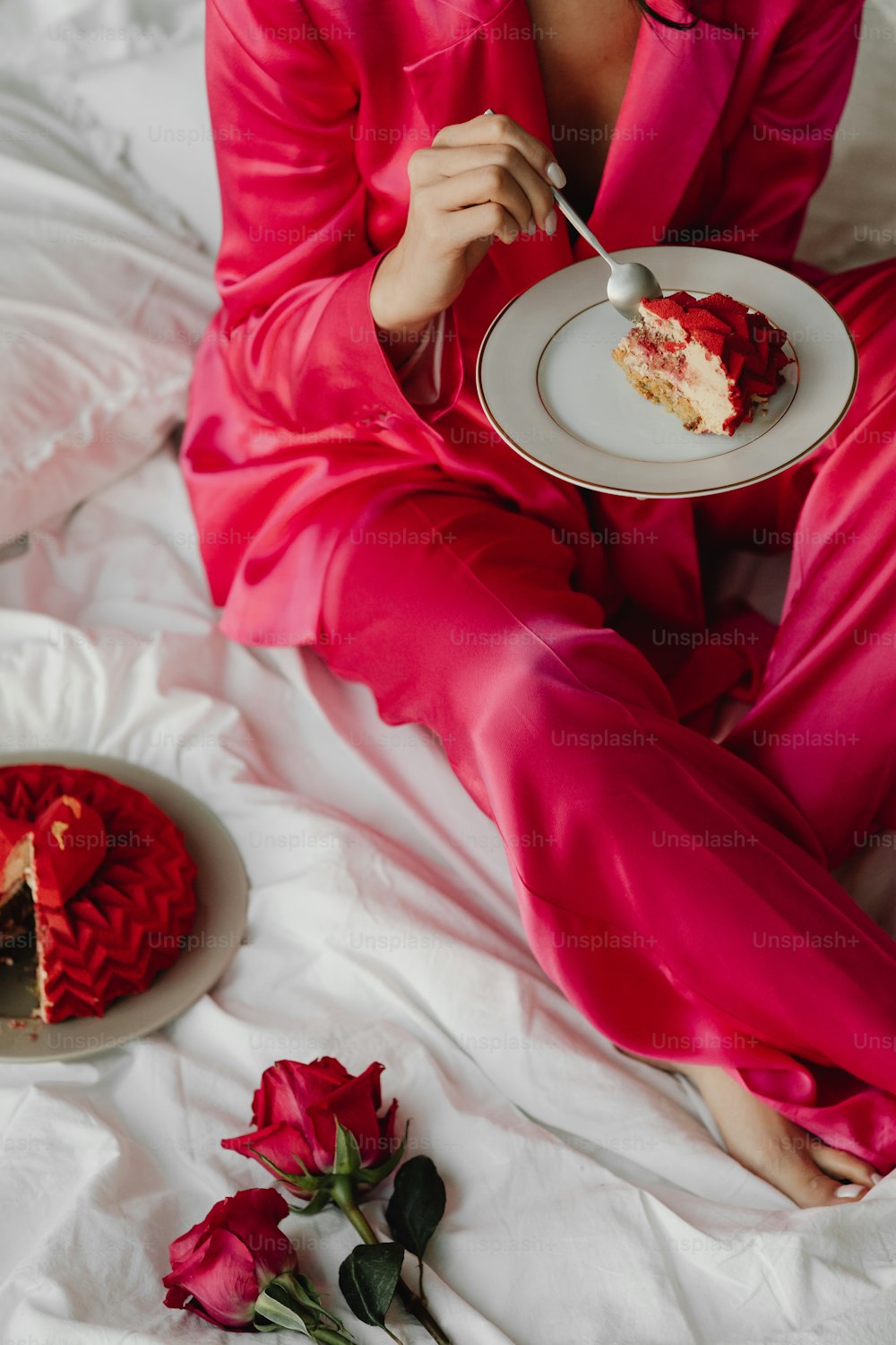 a woman in a pink suit eating a piece of cake
