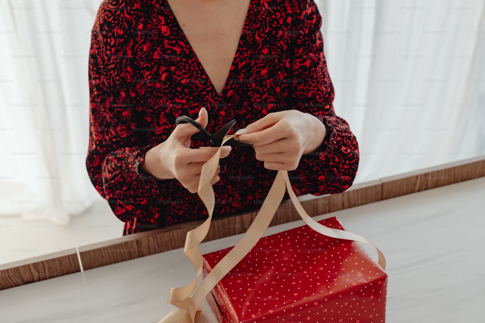 a woman is opening a red gift box