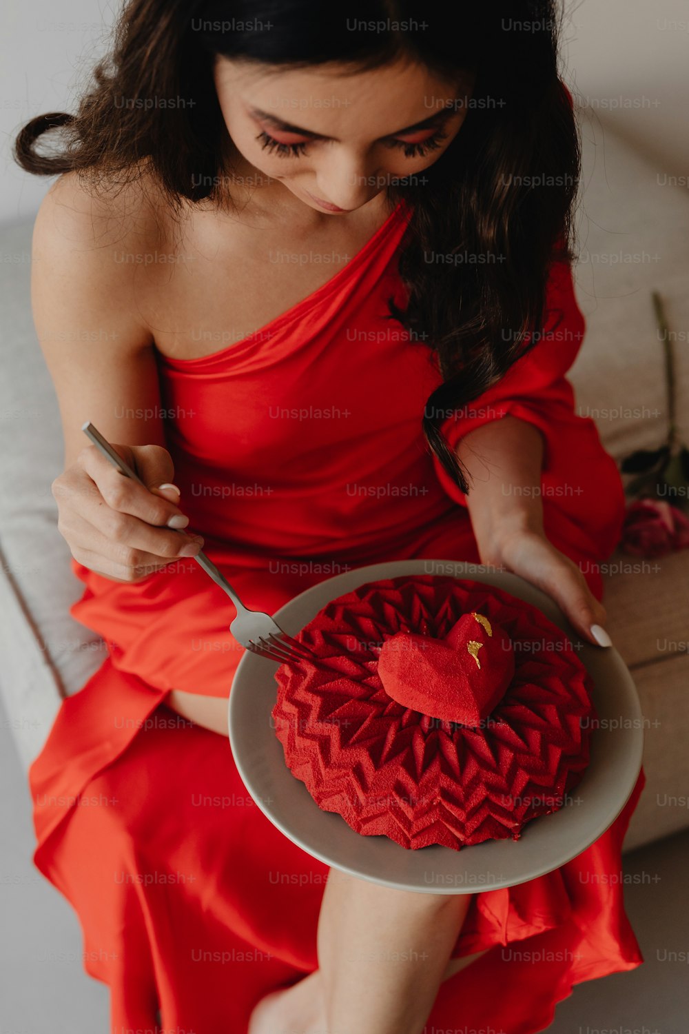 Una mujer con un vestido rojo sosteniendo un plato con un pastel