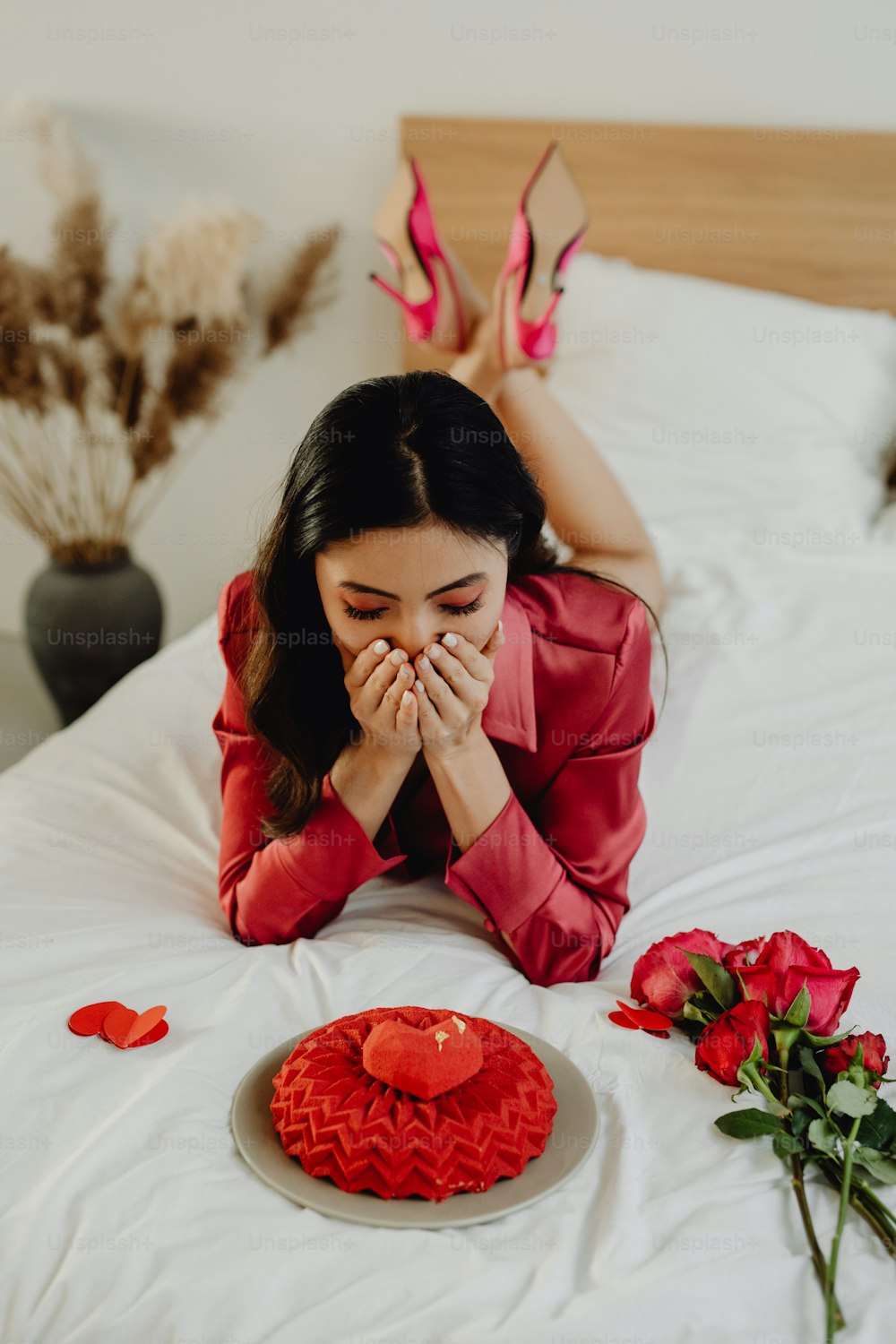 a woman laying on a bed next to a heart shaped cake