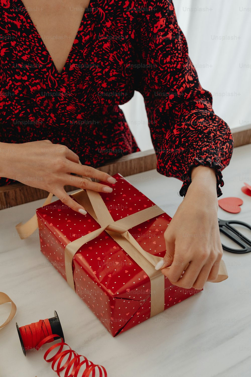 a woman is wrapping a red gift box