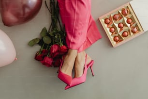 a woman's feet in pink shoes next to a box of candies