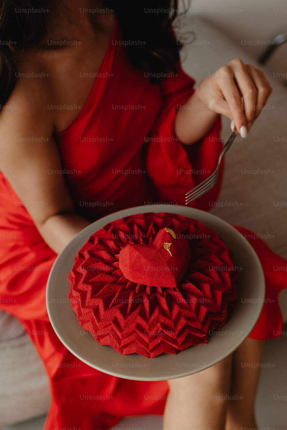 Eine Frau in einem roten Kleid hält einen herzförmigen Kuchen