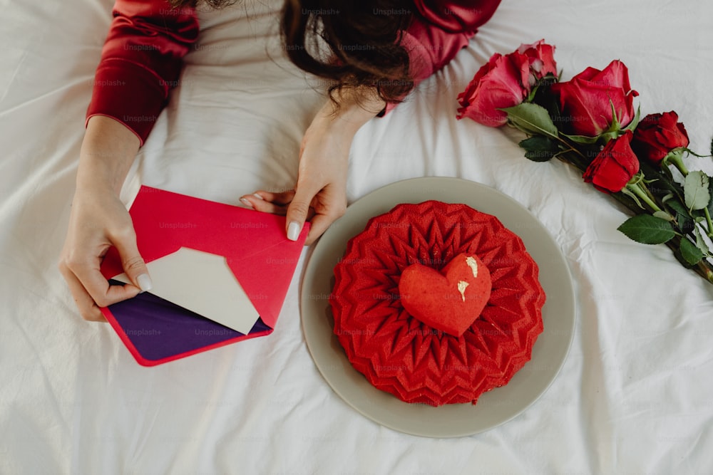 a woman laying on a bed next to a heart shaped cake