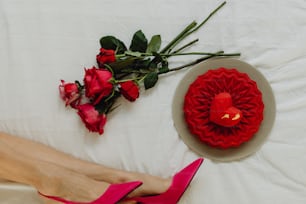 a woman's feet on a bed next to a red rose and a red