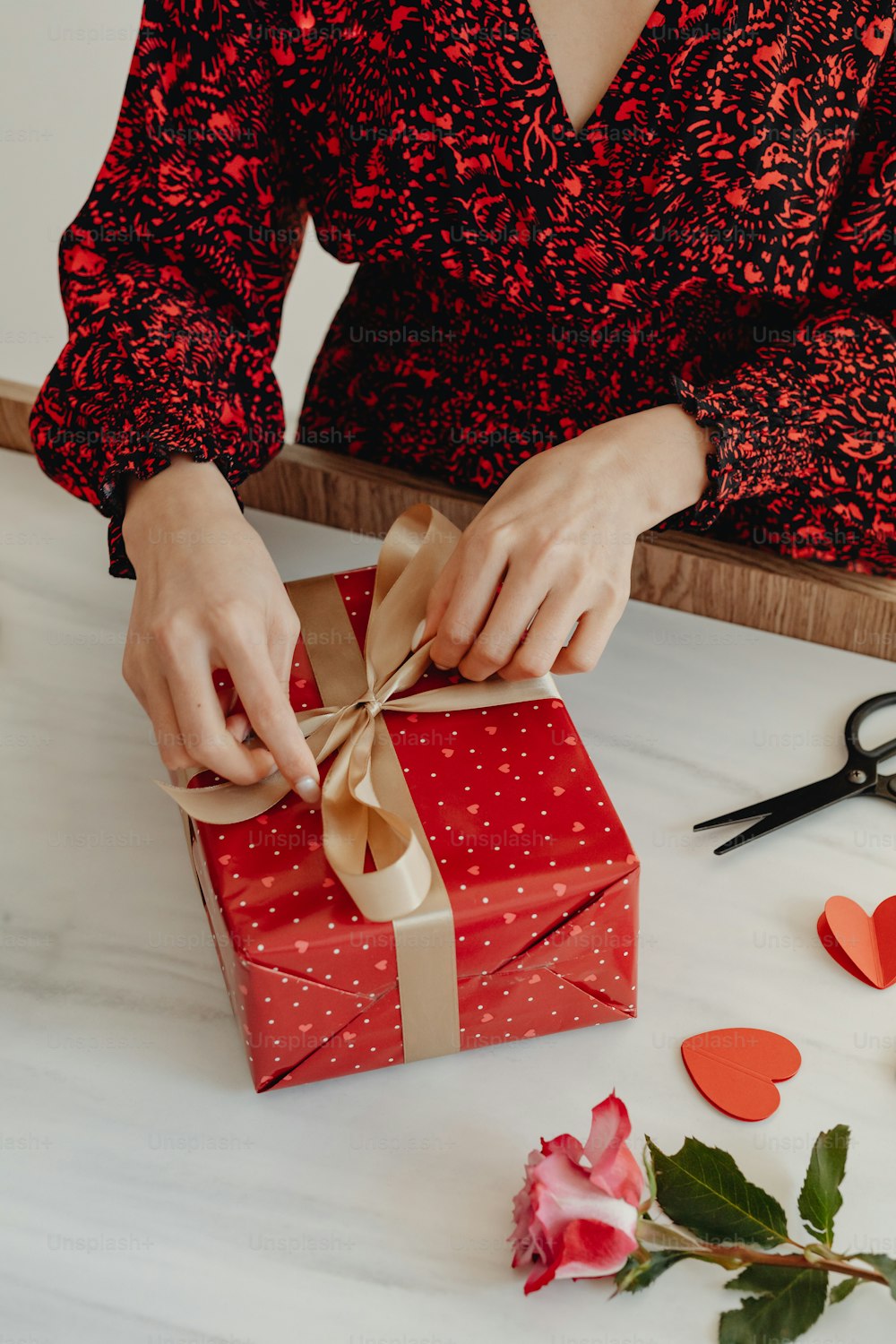 a woman is wrapping a gift with a brown ribbon