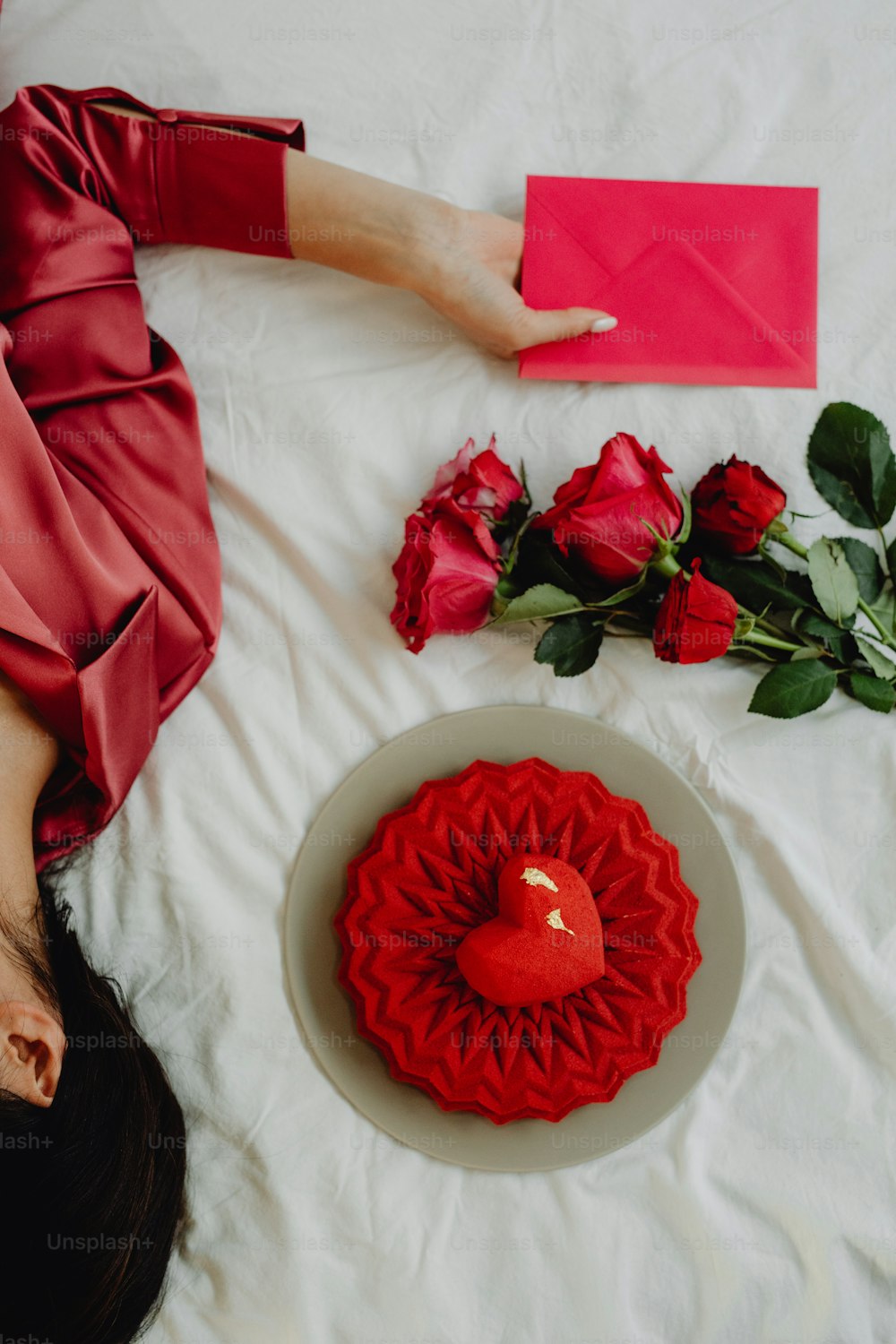 Una mujer acostada en una cama junto a una rosa roja