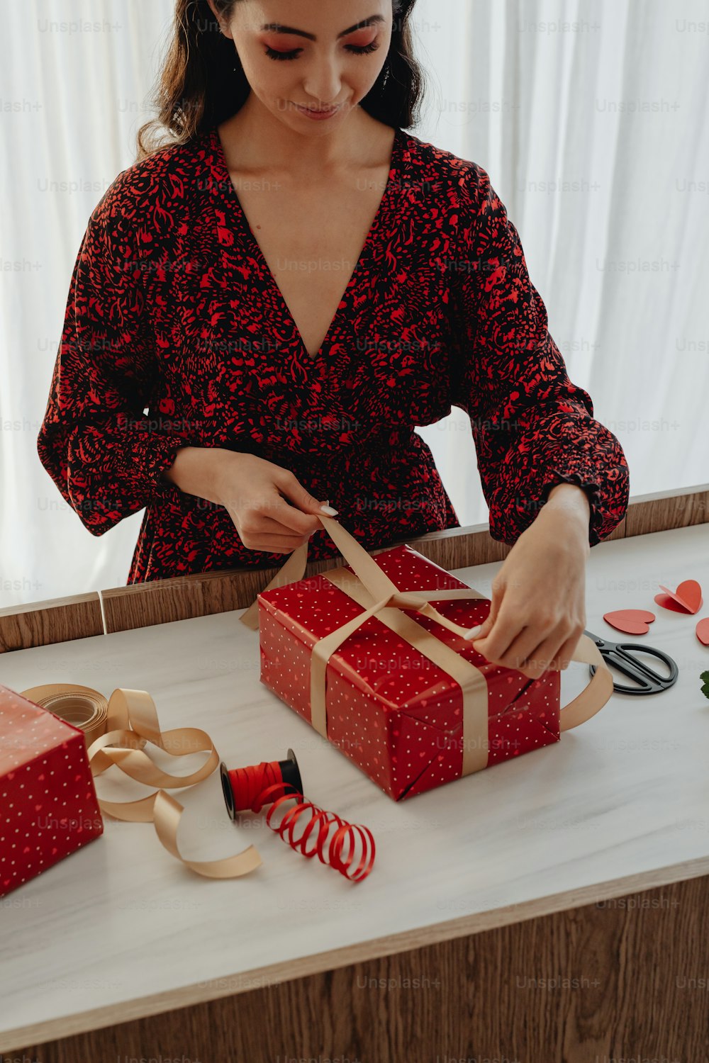 빨간 드레스를 입은 여자가 ��선물 상자를 열고 있다