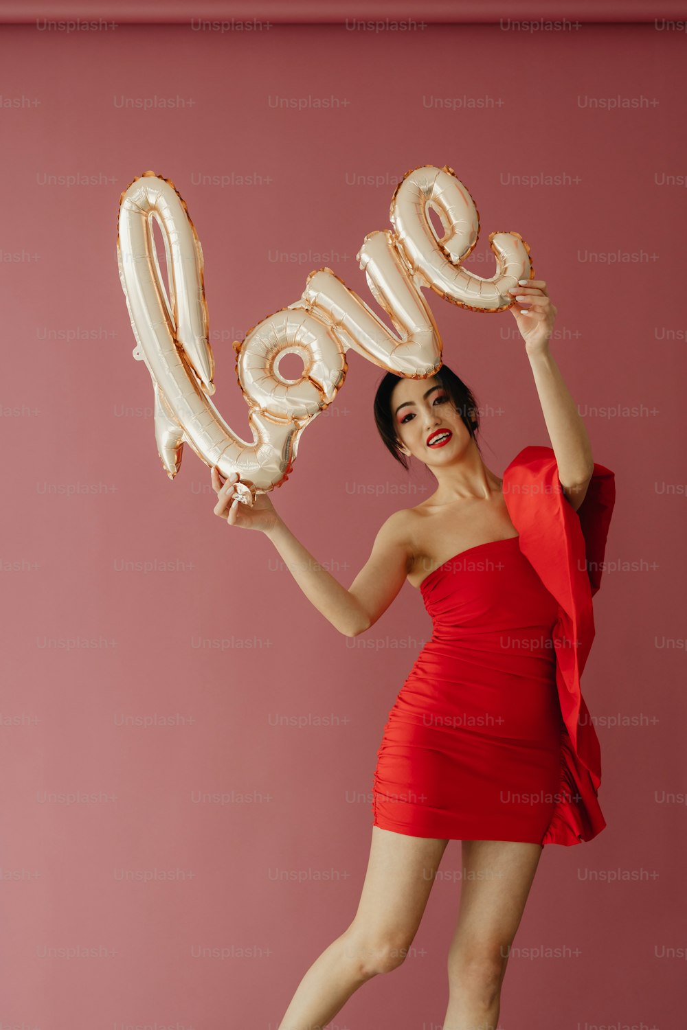 a woman in a red dress holding up a balloon that says love
