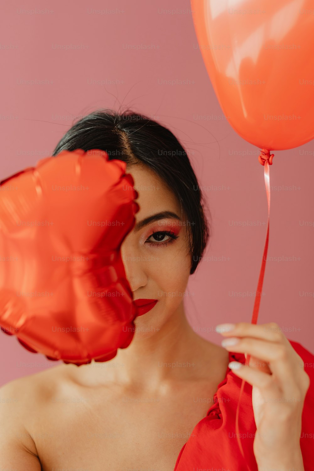 Eine Frau in einem roten Kleid, die einen roten Luftballon hält