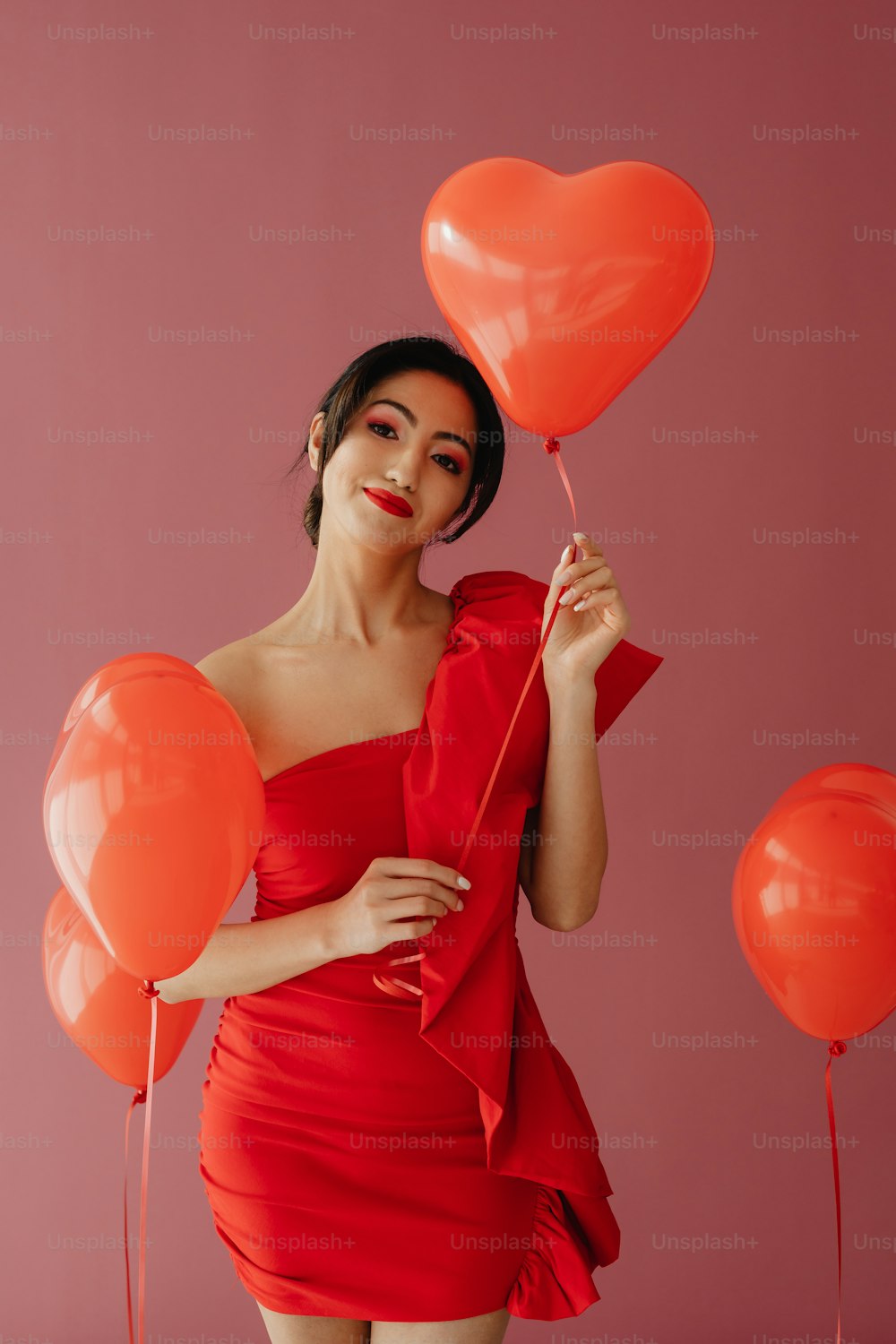 a woman in a red dress holding balloons