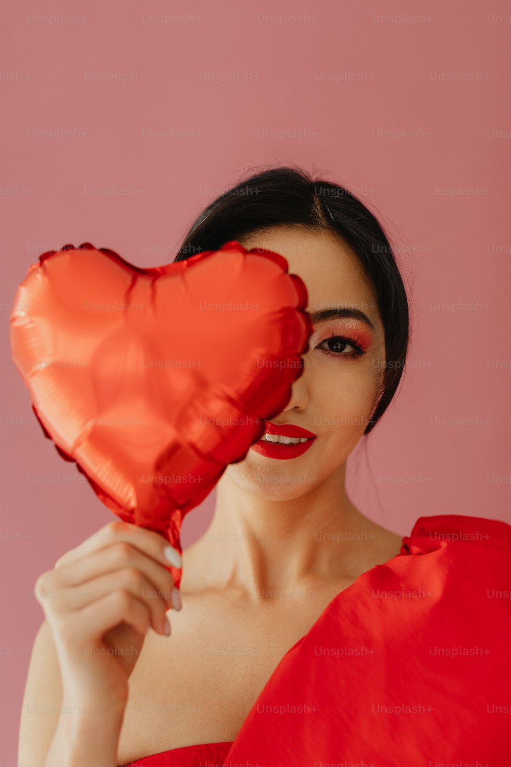 a woman in a red dress holding a heart shaped balloon