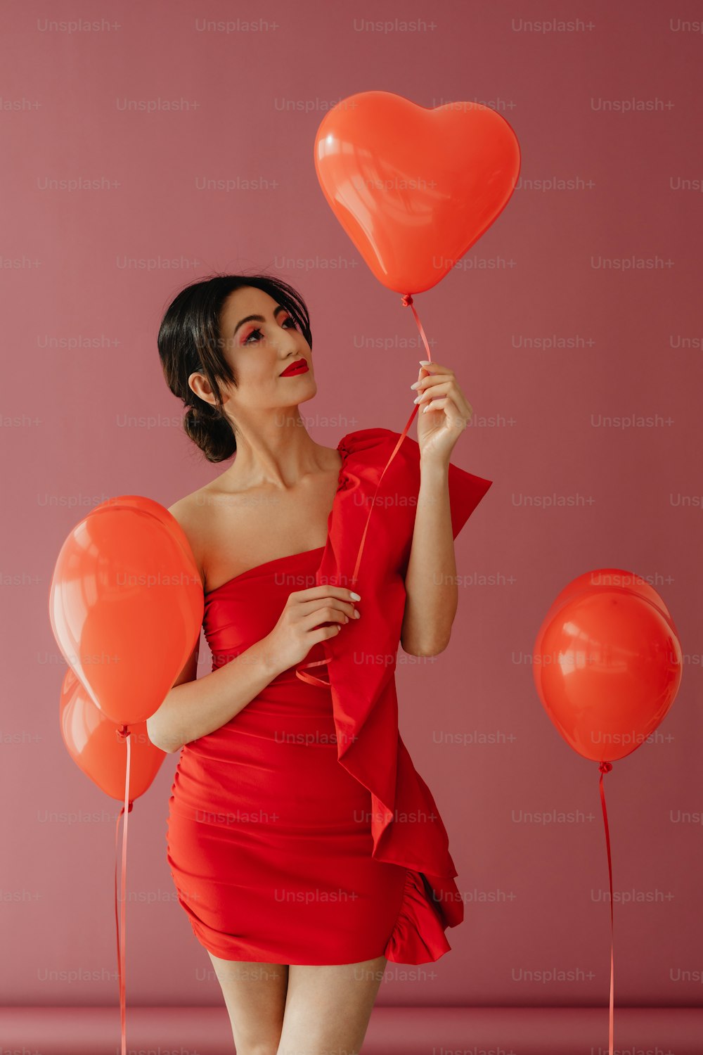 Una mujer con un vestido rojo sosteniendo globos