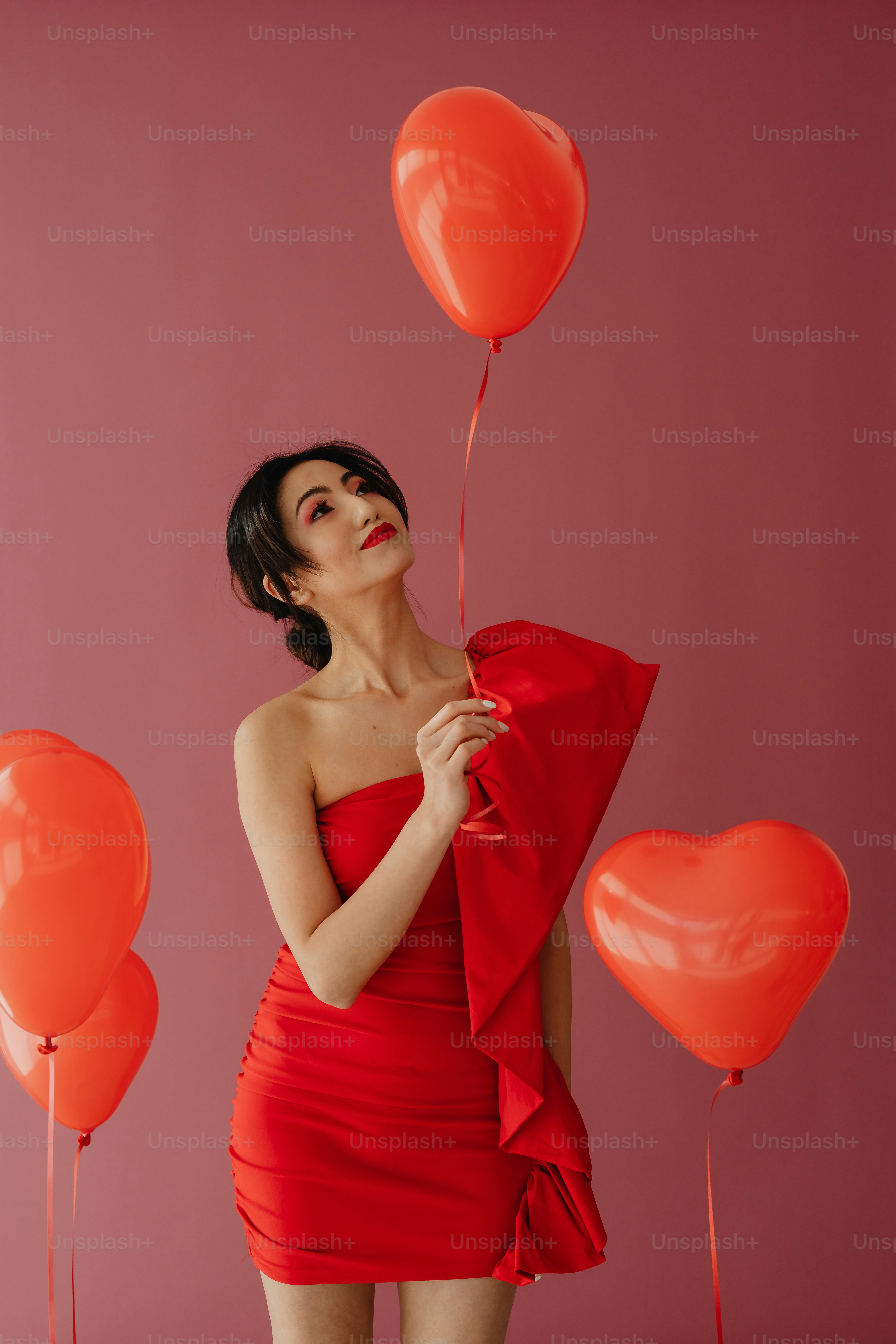 a woman in a red dress holding balloons