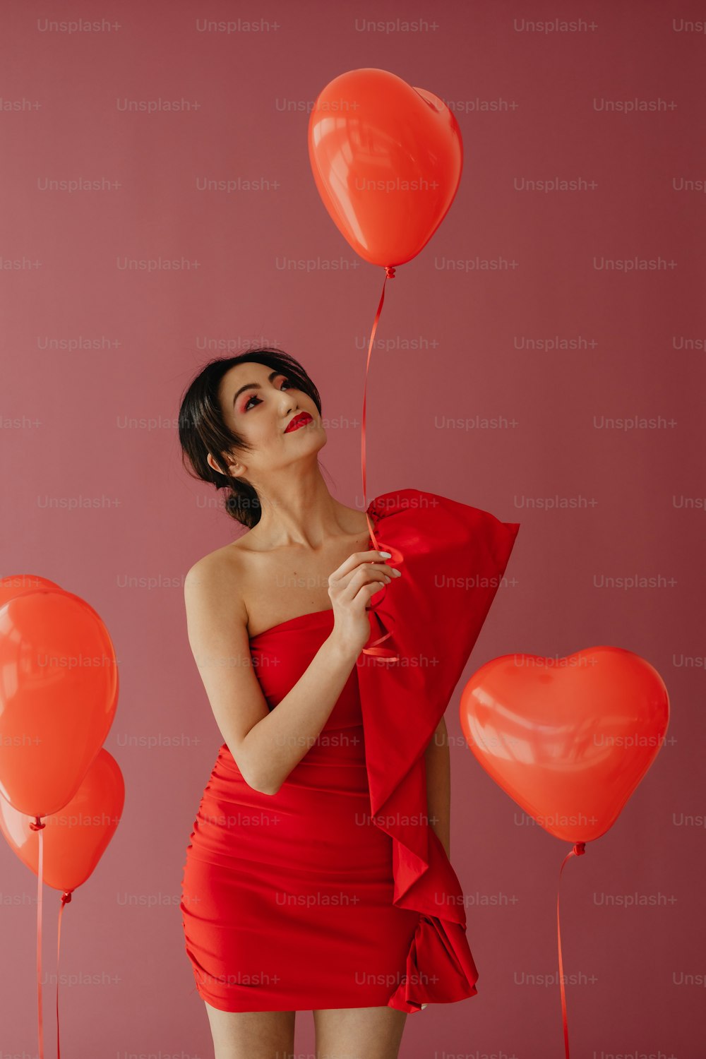 uma mulher em um vestido vermelho segurando balões