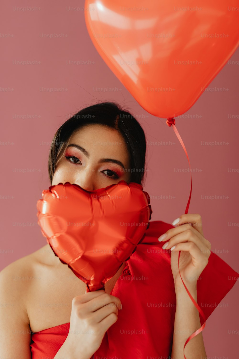 a woman holding a heart shaped balloon in front of her face