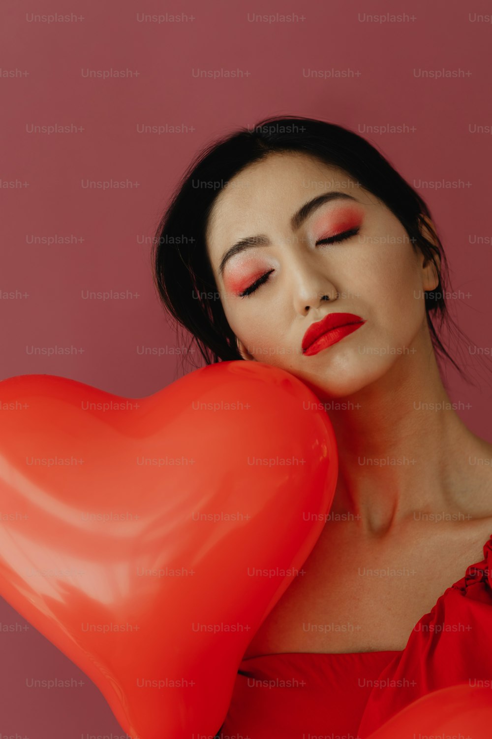 a woman in a red dress holding a heart shaped balloon