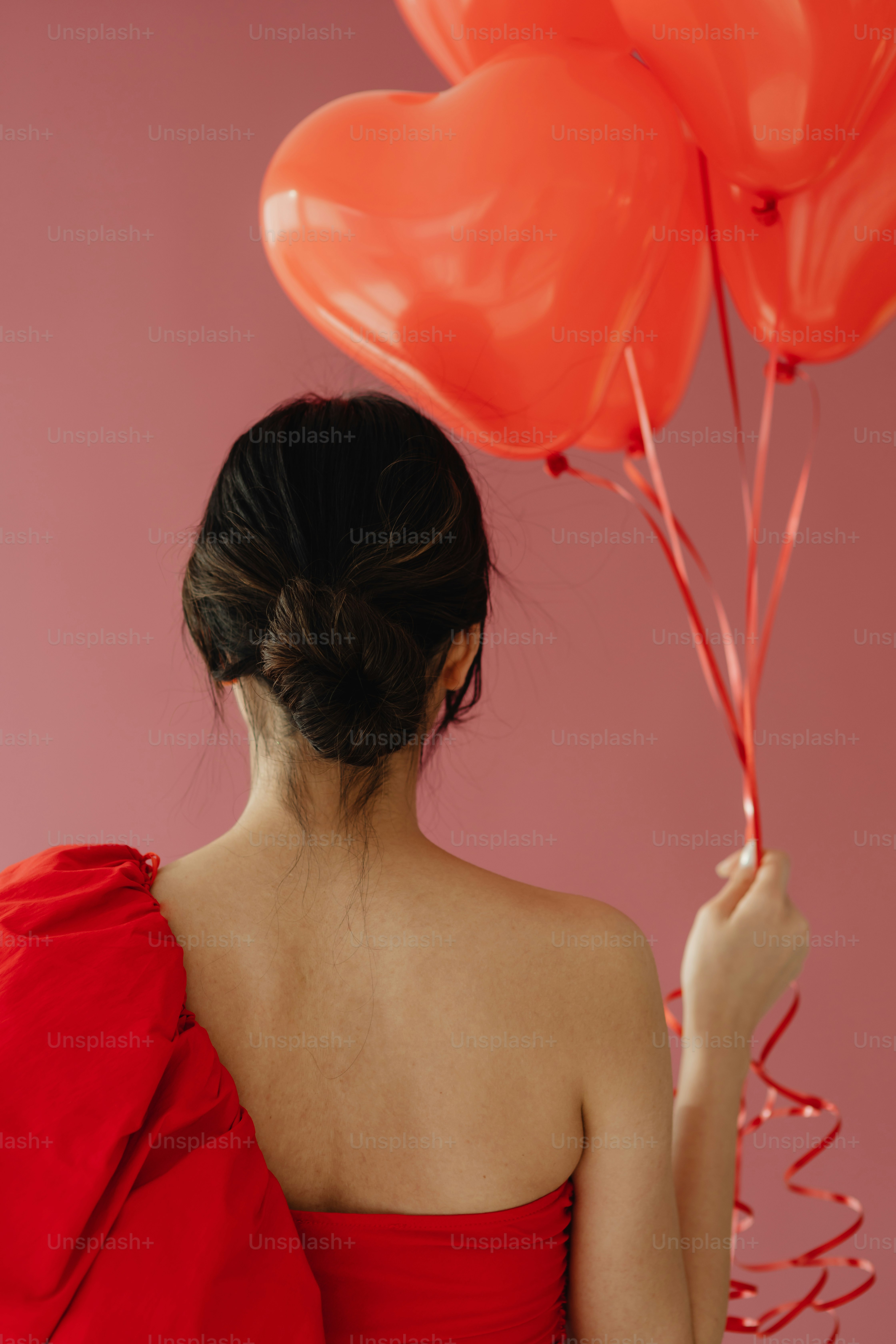 Une femme en robe rouge tenant des ballons rouges