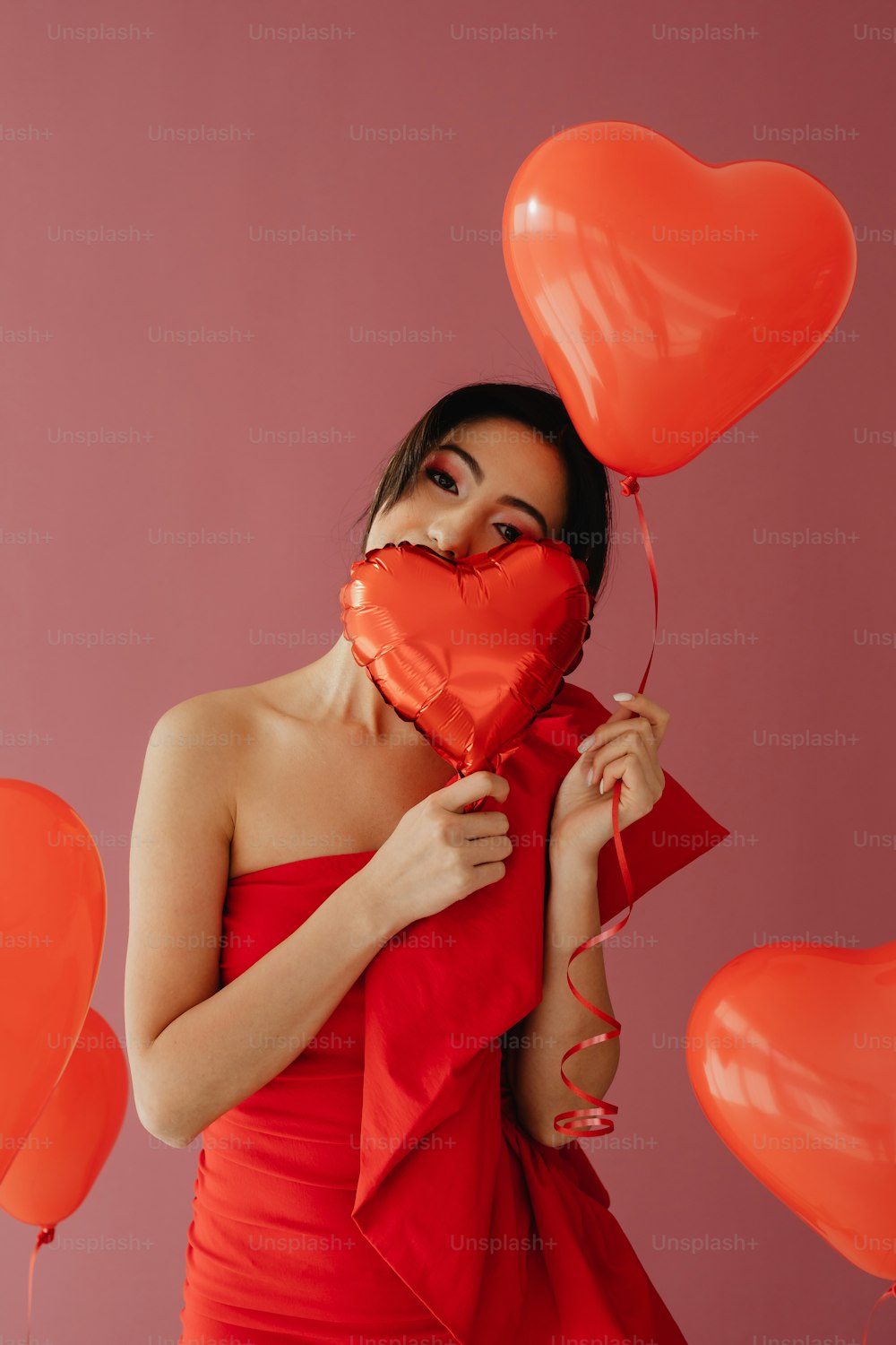 Eine Frau in einem roten Kleid, die einen herzförmigen Ballon hält