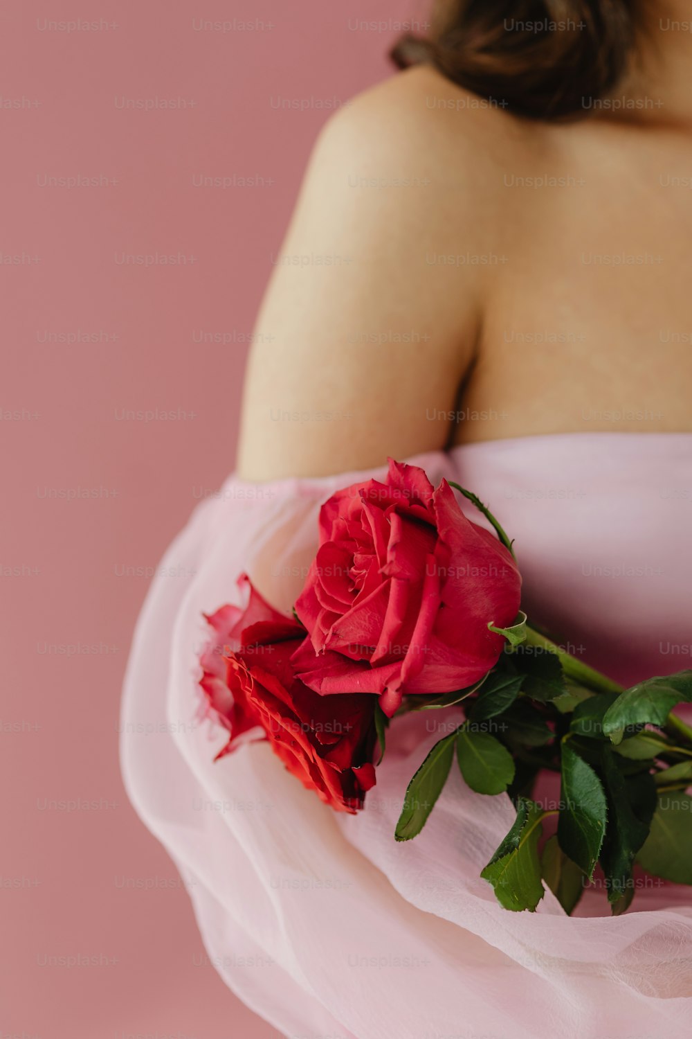 Eine Frau in einem rosa Kleid hält einen Rosenstrauß