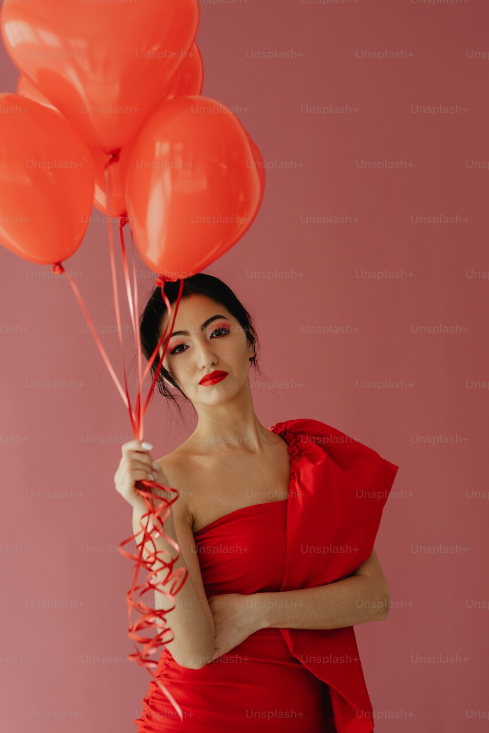 a woman in a red dress holding red balloons