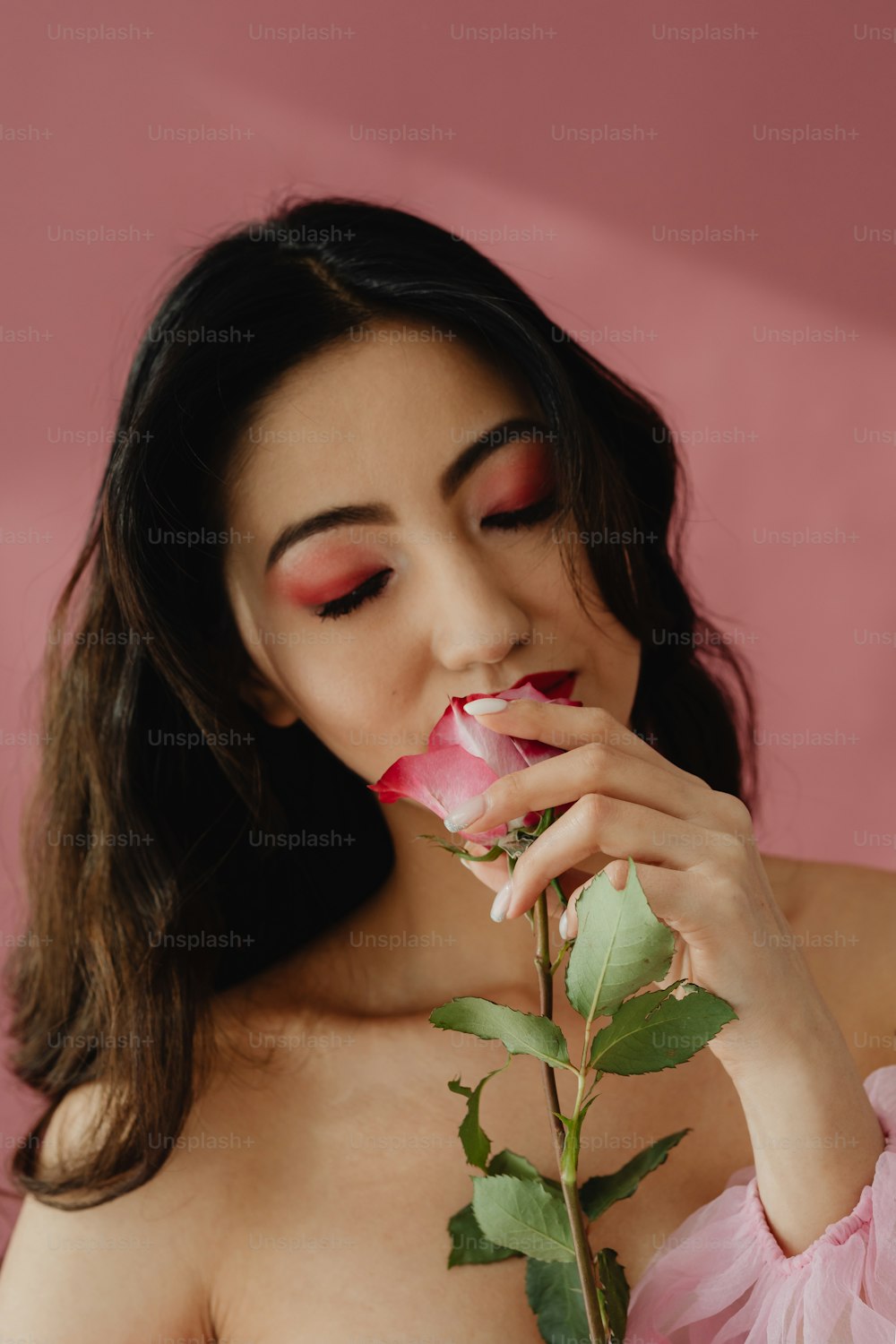 Una donna in un vestito rosa che tiene una rosa