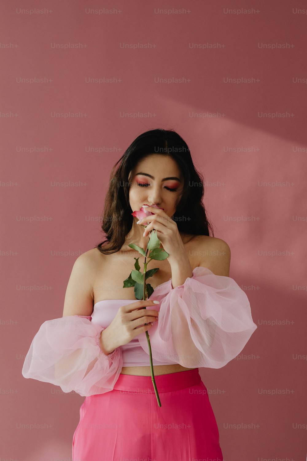 uma mulher em um top rosa segurando uma rosa