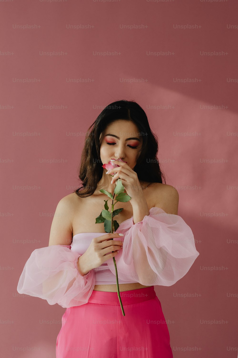 a woman in a pink top holding a rose