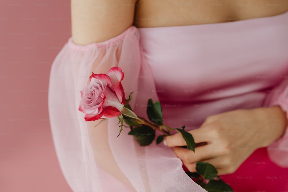 Una mujer con un vestido rosa sosteniendo una rosa