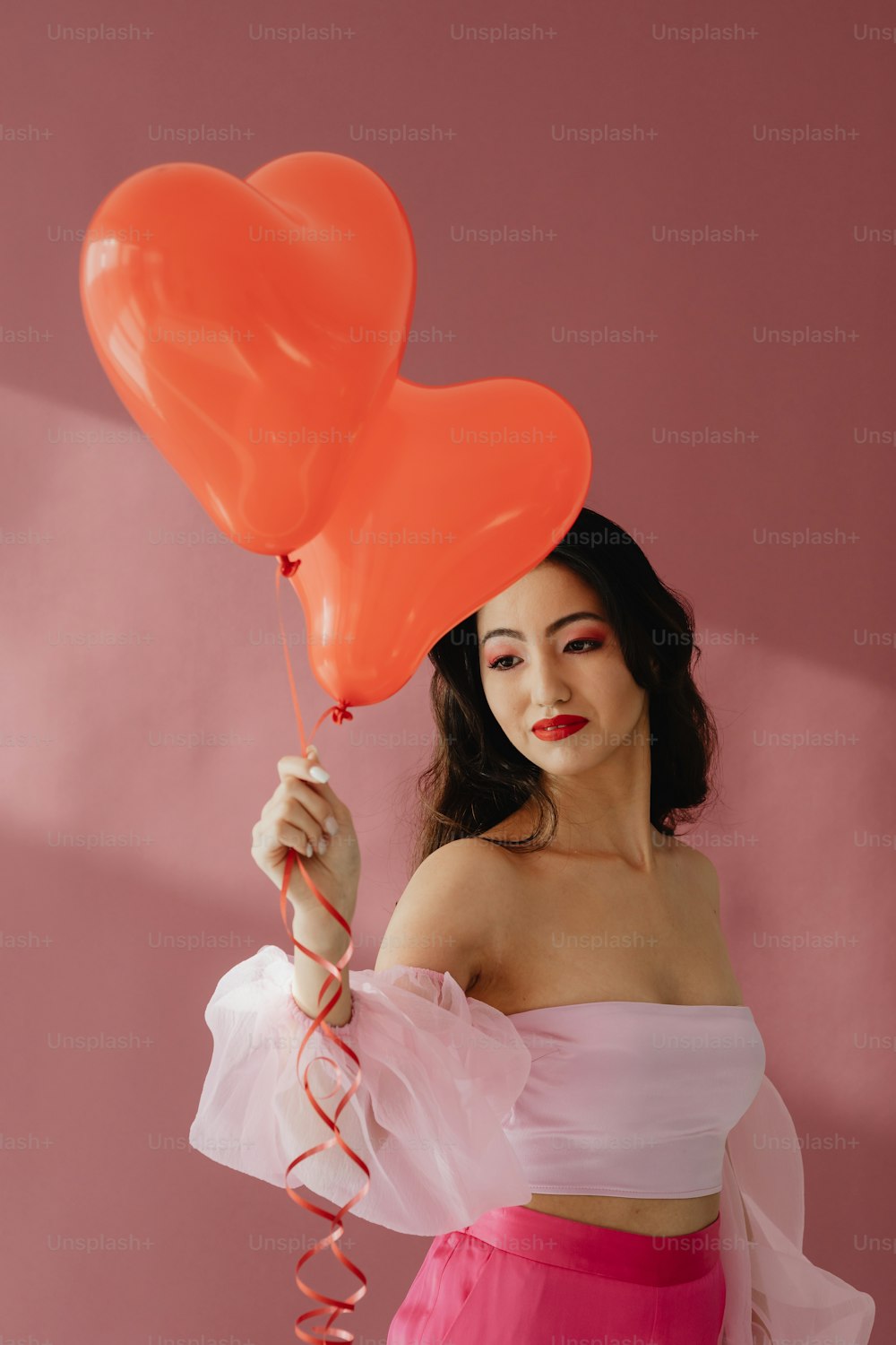 a woman holding two heart shaped balloons
